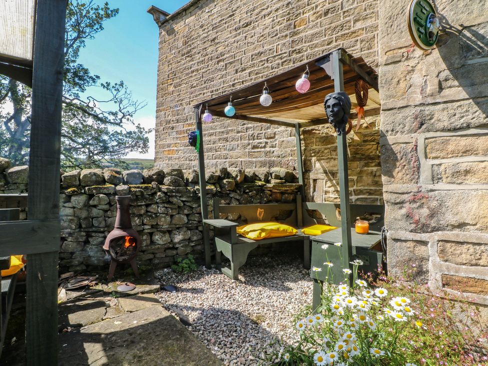 An outdoor seating area with a table and benches at Moldy Warp Barn Haworth