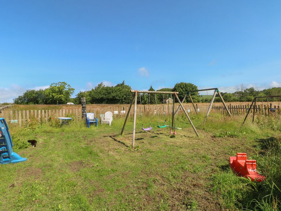 An outdoor play area with a swing set and slide at Moldy Warp Barn in Haworth