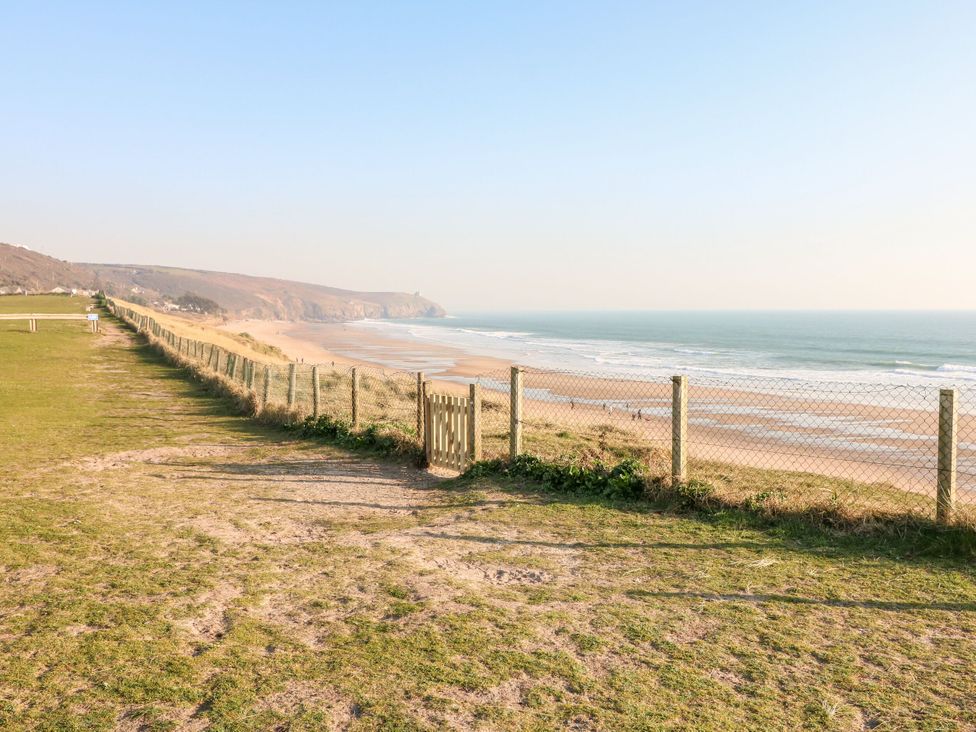 A beach scene with a fence and people walking at Stargazy Cottage, Praa Sands