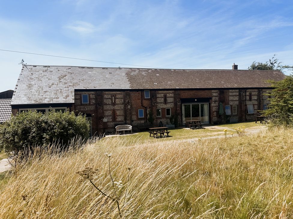 A building with tables and chairs in an outdoor area at Newfield Farm Cottages in Pimperne near Blandford Forum
