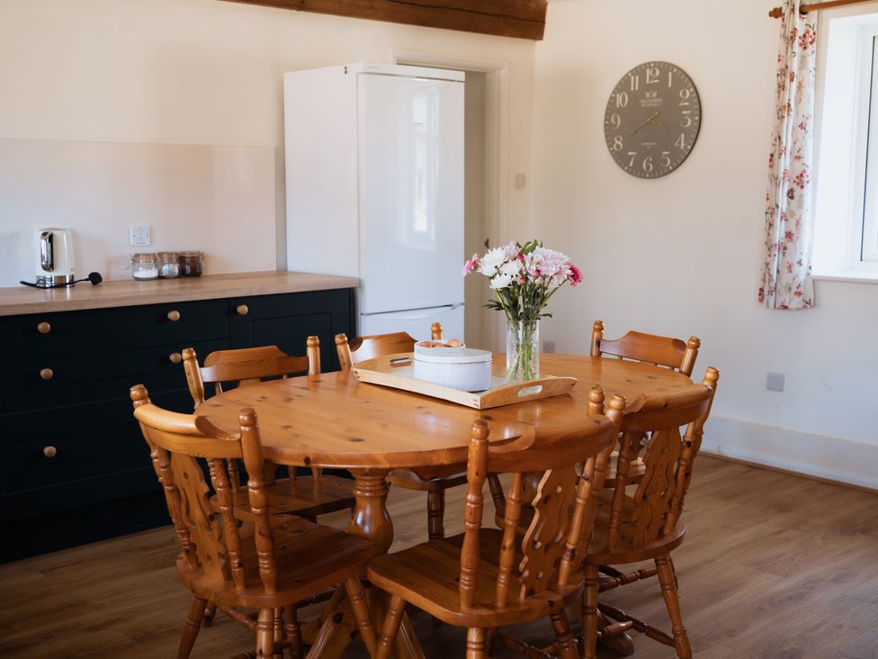 A kitchen with a round wooden table and chairs at Newfield Farm Cottages in Pimperne near Blandford Forum
