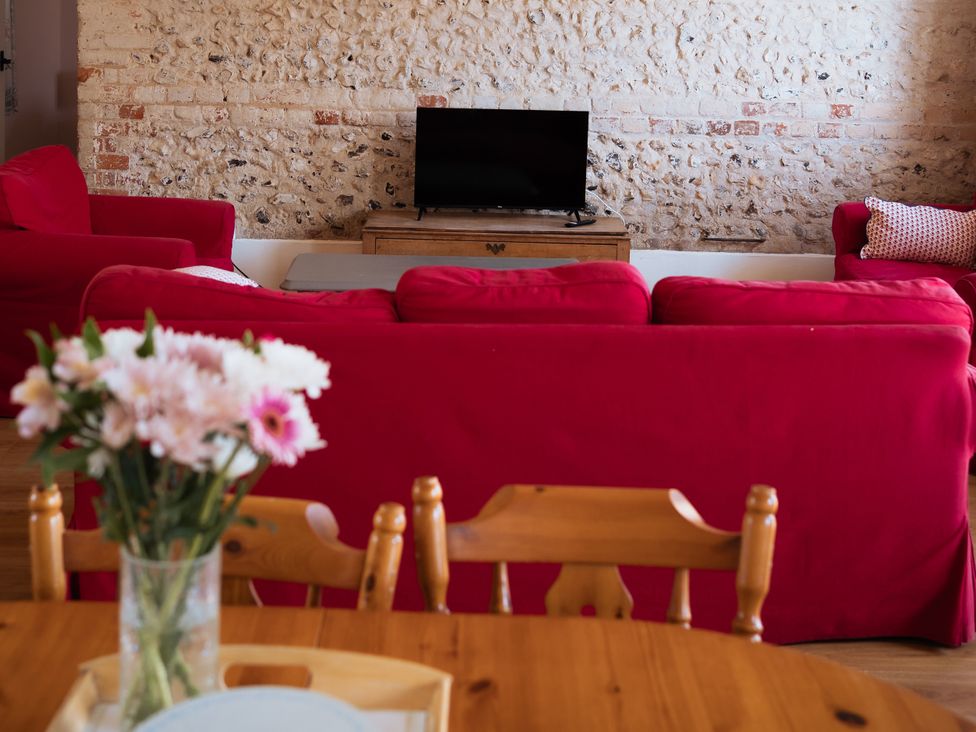 A living room with a television and red sofas at Newfield Farm Cottages Pimperne near Blandford Forum