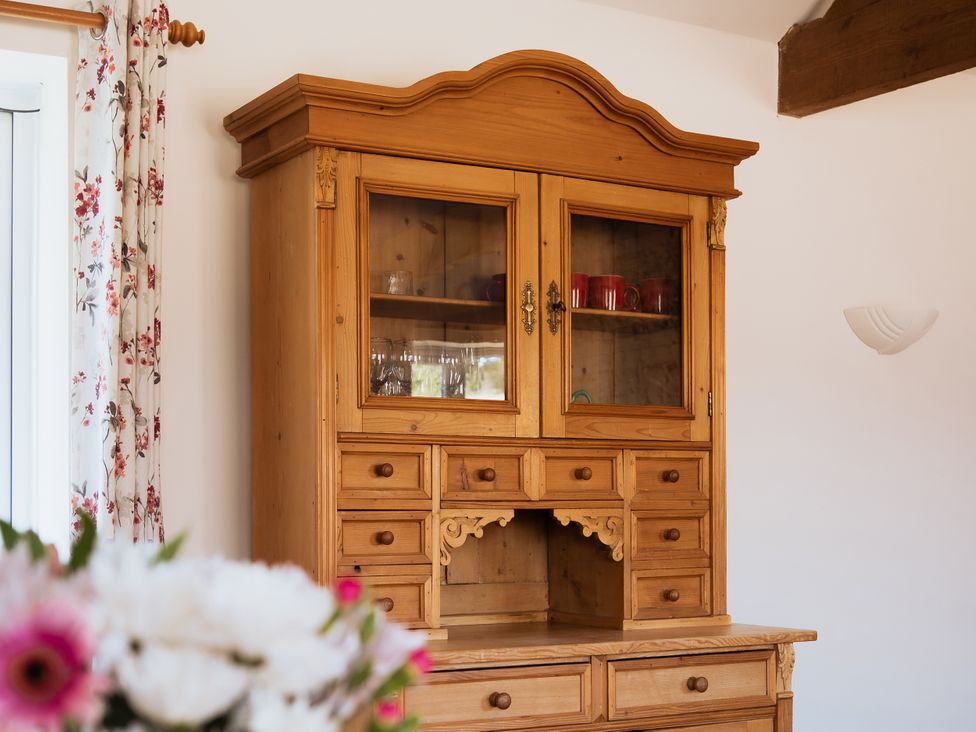 A wooden cupboard with shelves and mugs at Newfield Farm Cottages Pimperne near Blandford Forum