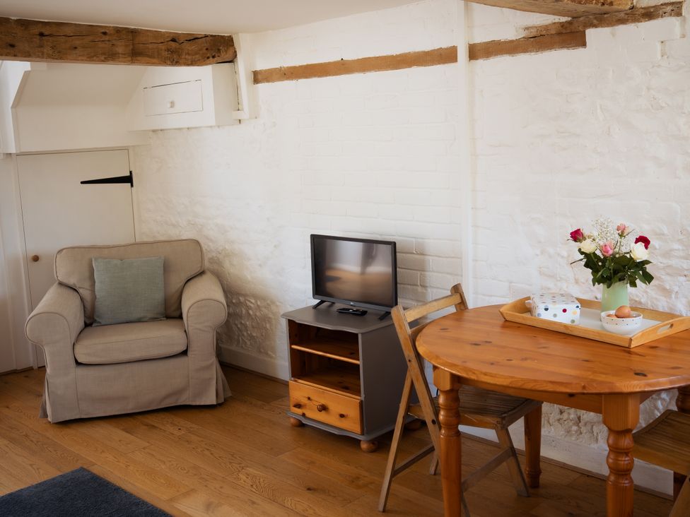 A living room with an armchair and dining table at Newfield Farm Cottages in Pimperne near Blandford Forum