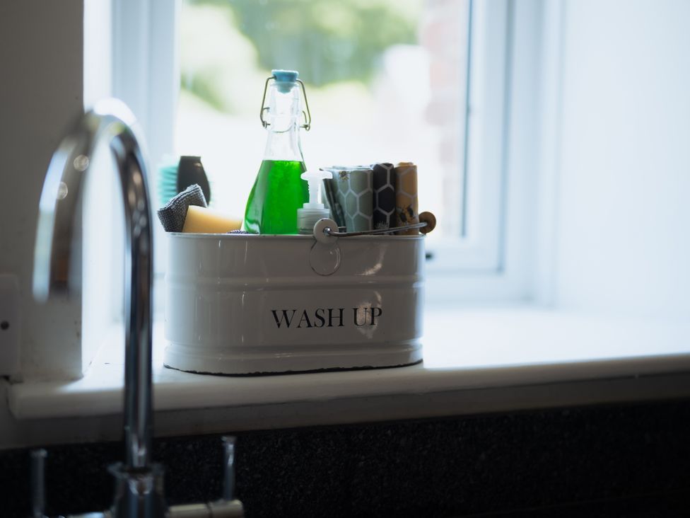 A sink with a container of cleaning supplies at Newfield Farm Cottages Pimperne near Blandford Forum