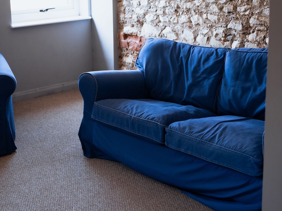 A living room with a blue sofa and stone wall at Newfield Farm Cottages in Pimperne near Blandford Forum
