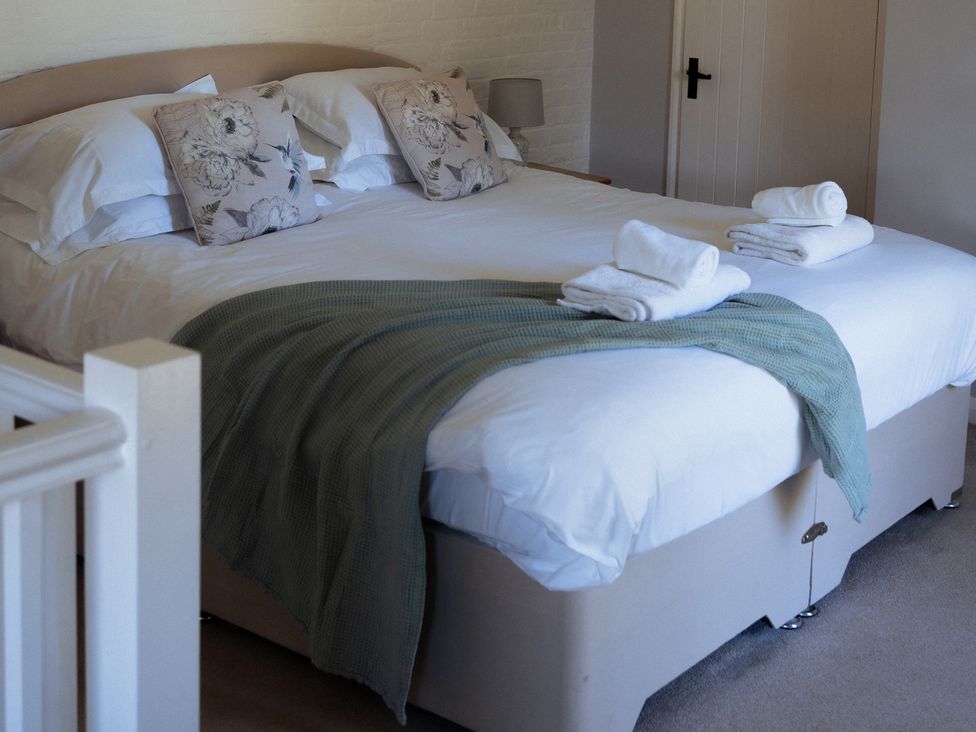 A bedroom with a double bed and towels at Newfield Farm Cottages in Pimperne near Blandford Forum
