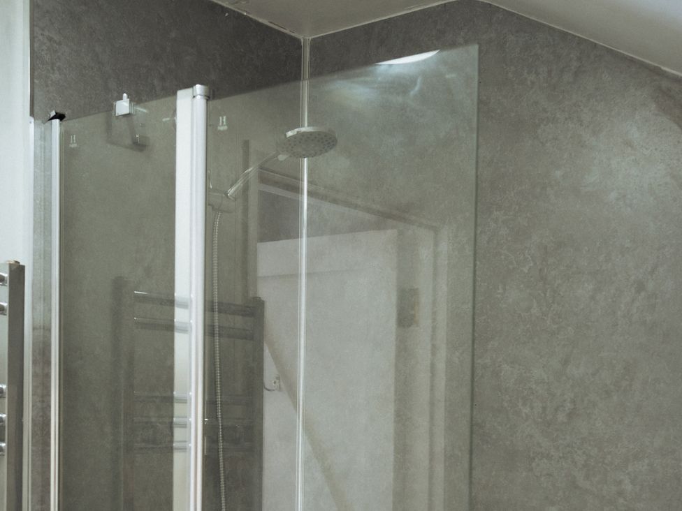 A shower with glass partition and shower head at Newfield Farm Cottages Pimperne near Blandford Forum