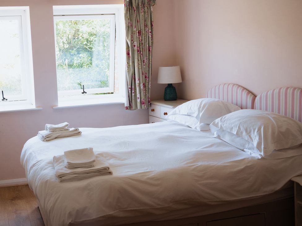 A bedroom with a bed and windows at Newfield Farm Cottages in Pimperne near Blandford Forum