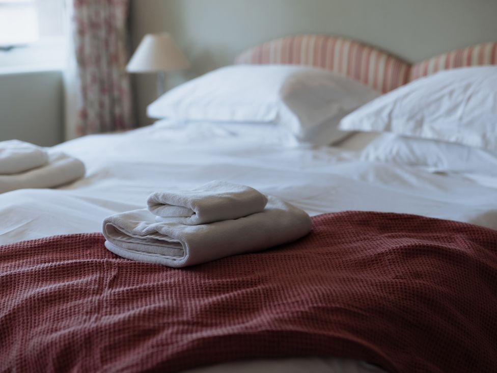 A bedroom with a made bed and towels at Newfield Farm Cottages in Pimperne near Blandford Forum