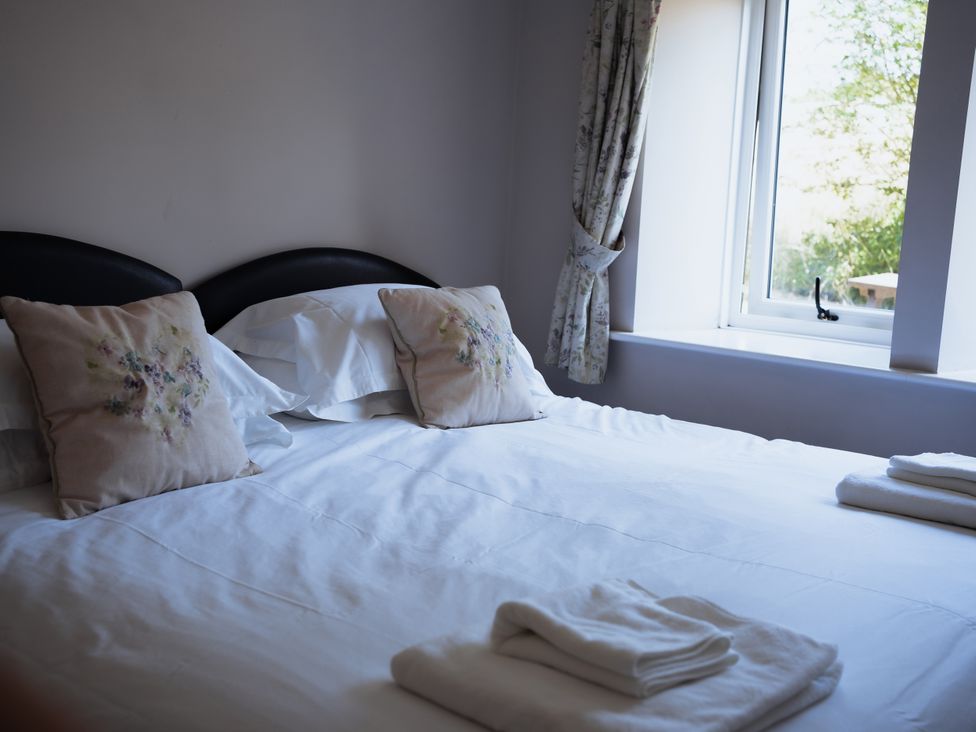 A bedroom with a bed and window at Newfield Farm Cottages in Pimperne near Blandford Forum