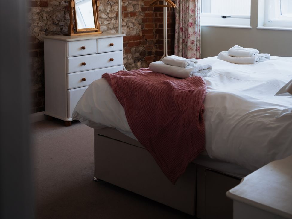 A bedroom with a bed, towels, and a chest of drawers at Newfield Farm Cottages in Pimperne near Blandford Forum