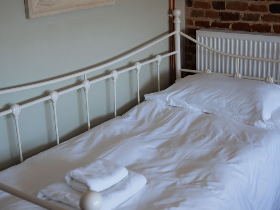 A bed with white sheets and towels in the bedroom at Newfield Farm Cottages Pimperne near Blandford Forum