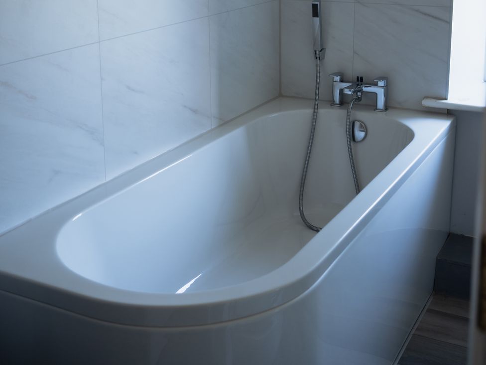 A bathtub with a faucet and showerhead at Newfield Farm Cottages Pimperne near Blandford Forum