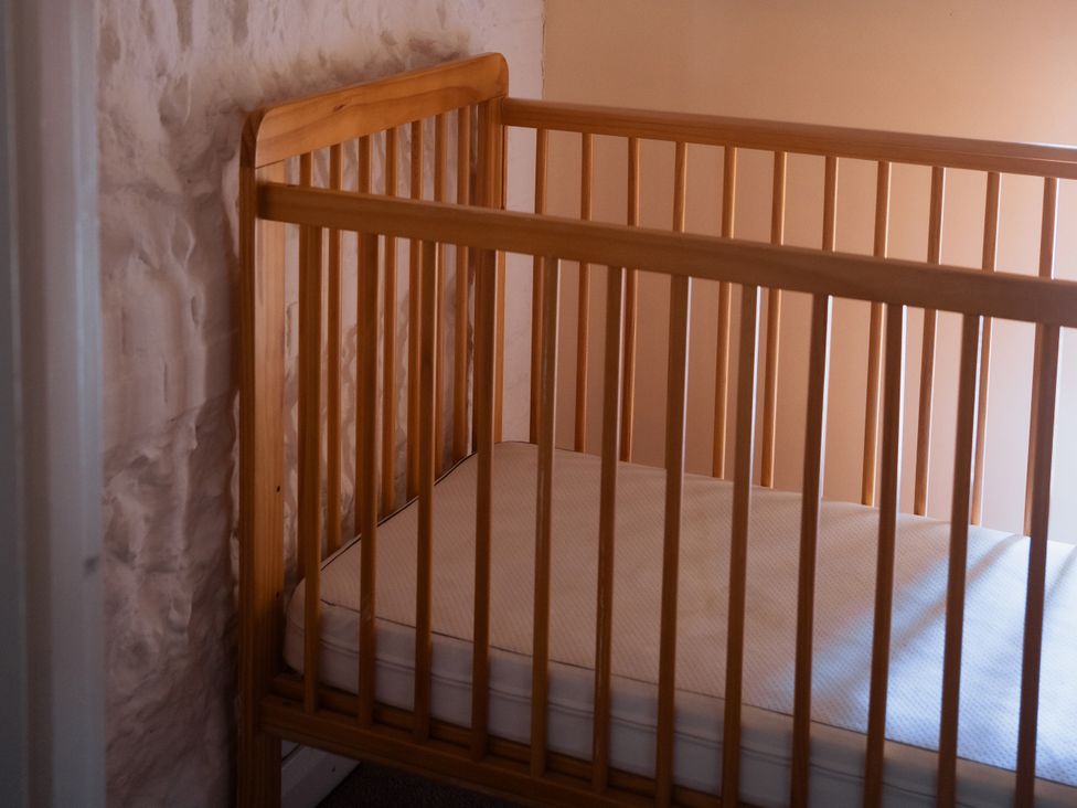 A nursery with a wooden crib at Newfield Farm Cottages in Pimperne near Blandford Forum