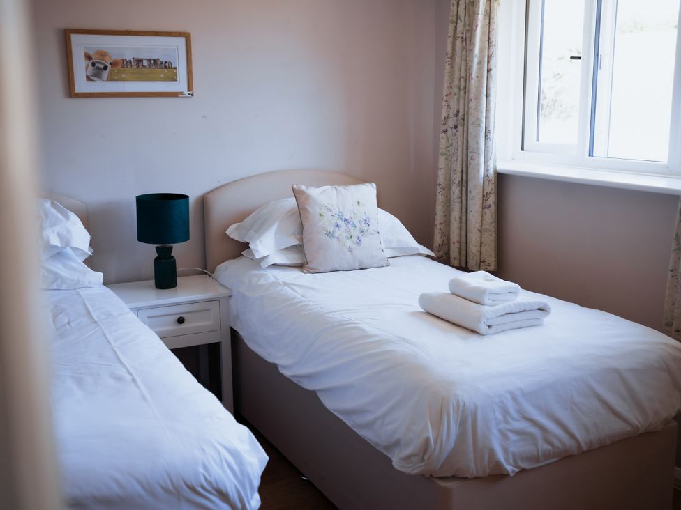 A bedroom with two beds and a lamp on a bedside table at Newfield Farm Cottages Pimperne near Blandford Forum