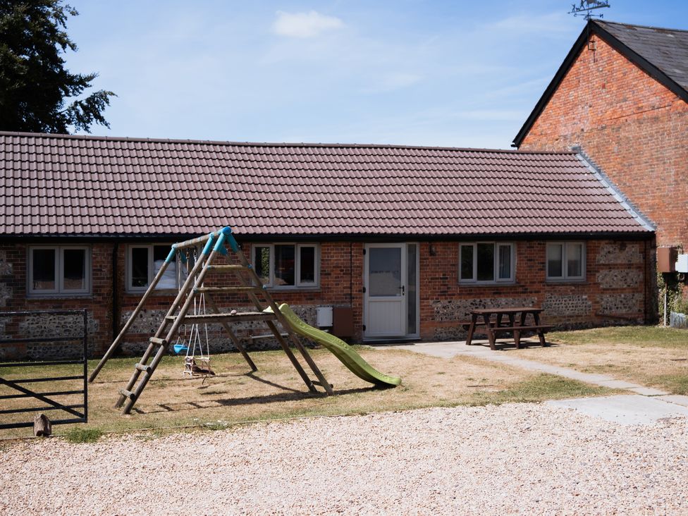 An outdoor area with a building and playground equipment at Newfield Farm Cottages Pimperne near Blandford Forum