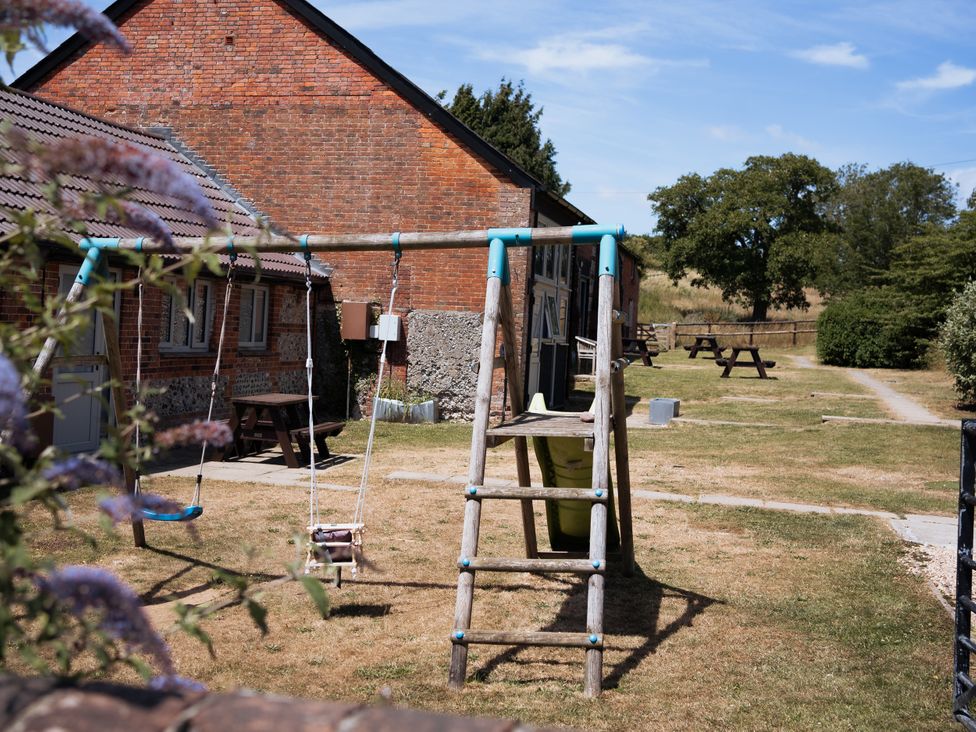 An outdoor area with a swing set and picnic tables at Newfield Farm Cottages Pimperne near Blandford Forum