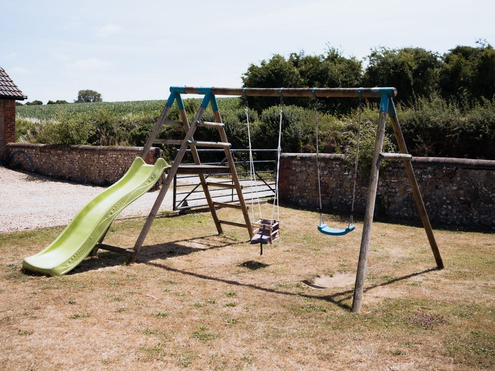 A playground with a slide and swing set at Newfield Farm Cottages Pimperne near Blandford Forum