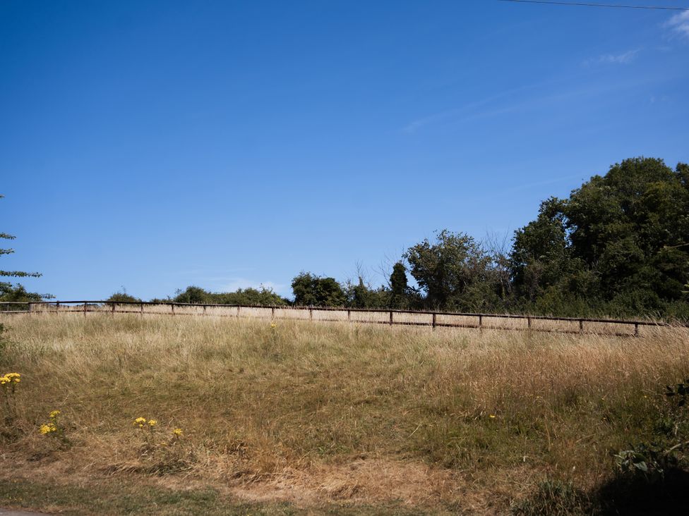 A grassy area with a fence and trees at Newfield Farm Cottages in Pimperne near Blandford Forum