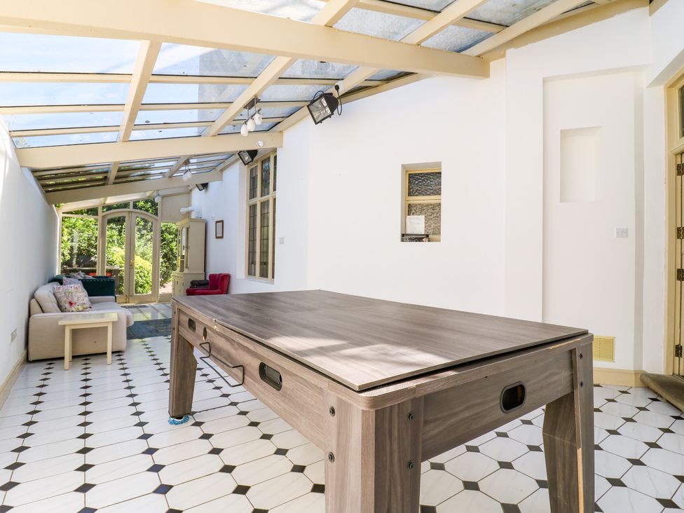 A conservatory with a table and seating area at The Chestnuts in Peterborough