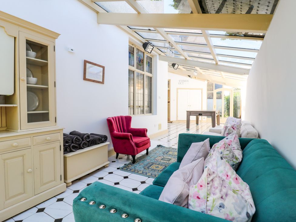 A conservatory with sofas and a table at The Chestnuts in Peterborough
