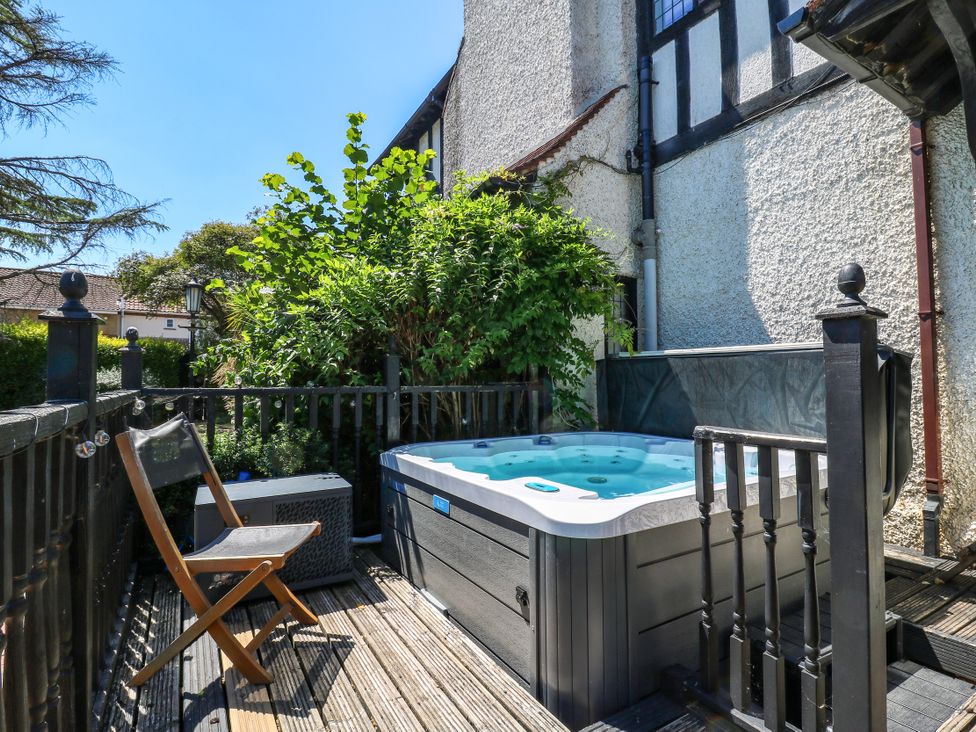 A hot tub on a deck with plants and a chair at The Chestnuts in Peterborough