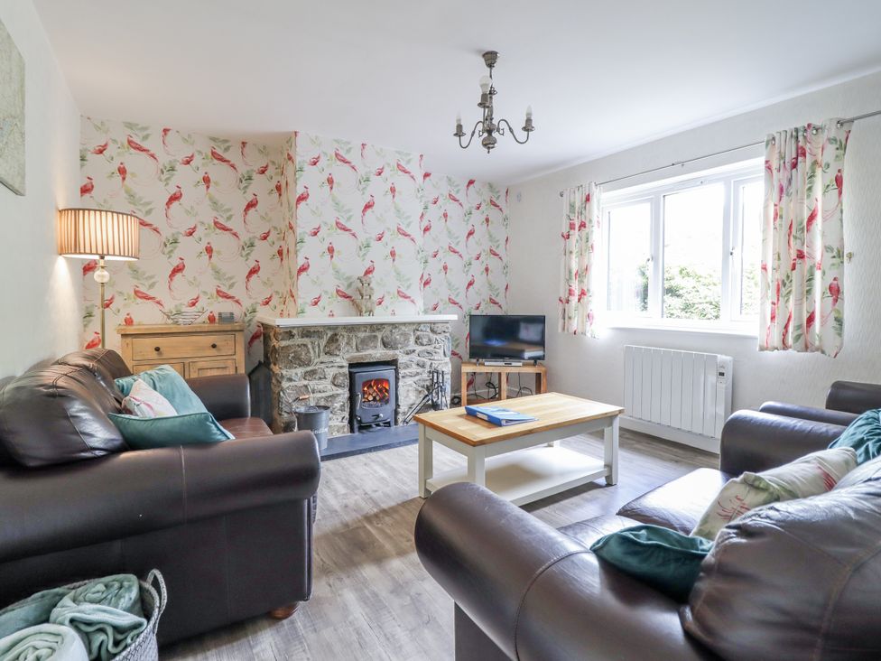 A living room with couches, a coffee table, and a fireplace at 8 Glan Ysgethin in Barmouth