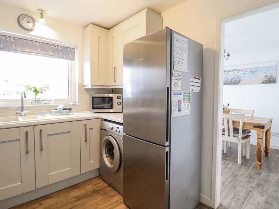 A kitchen with a refrigerator, washing machine, and microwave at 8 Glan Ysgethin in Barmouth