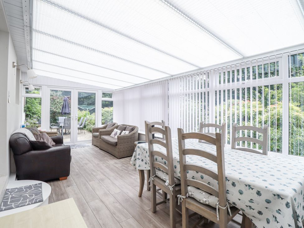 A conservatory with a table and chairs and a sofa at 8 Glan Ysgethin in Barmouth