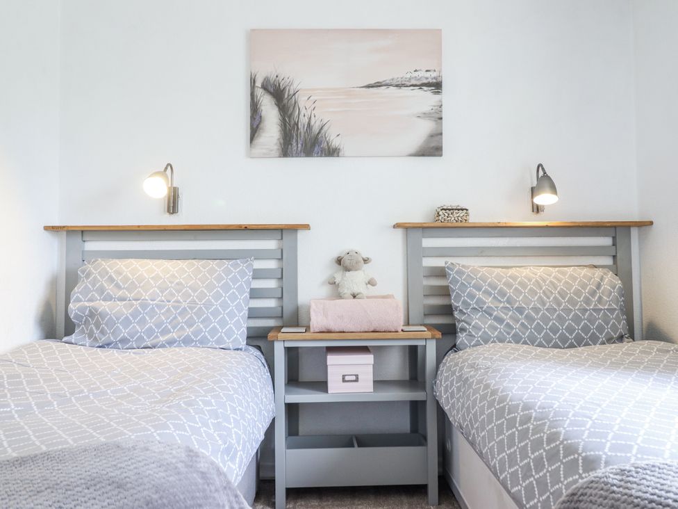 A bedroom with two beds and a painting at 8 Glan Ysgethin in Barmouth