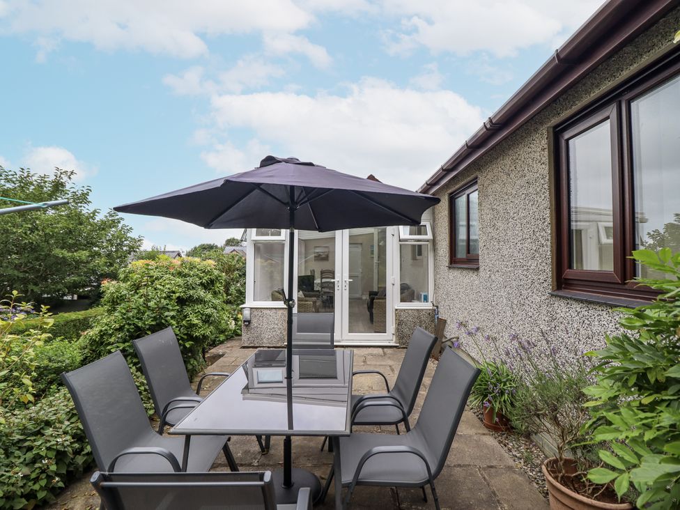 A garden with a table and chairs under an umbrella at 8 Glan Ysgethin in Barmouth