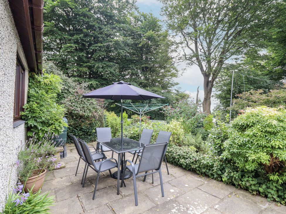 A garden with a table and chairs under an umbrella at 8 Glan Ysgethin in Barmouth