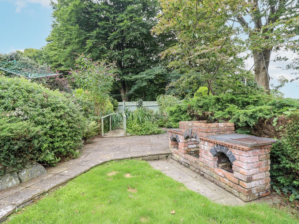 A garden with a barbecue and pathway at 8 Glan Ysgethin in Barmouth