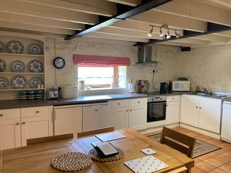 A kitchen with cabinets, clock, and table at The Granary in Mansergh near Kirkby Lonsdale