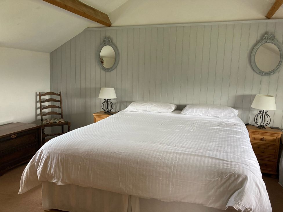 A bedroom with a bed, lamp, mirror, chair, and dresser at The Granary near Kirkby Lonsdale