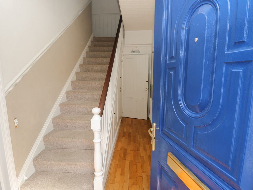 A hallway with a staircase and blue front door at Lancaster House Sandown