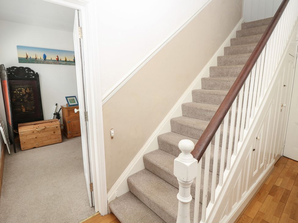 A staircase and hallway with a chest and picture at Lancaster House in Sandown
