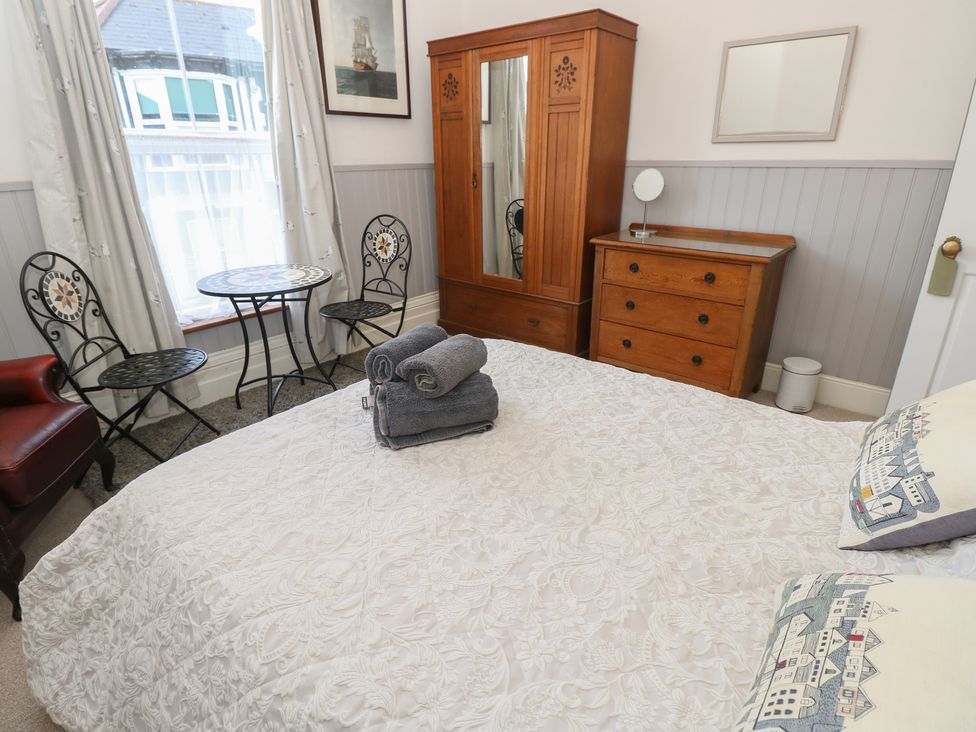 A bedroom with a bed, wardrobe, and a table with chairs at Lancaster House Sandown