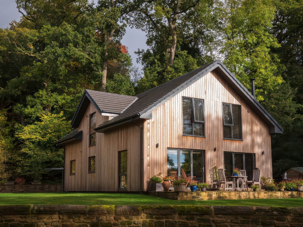 A house with wooden siding and patio furniture at Romsey Lodge in Wark