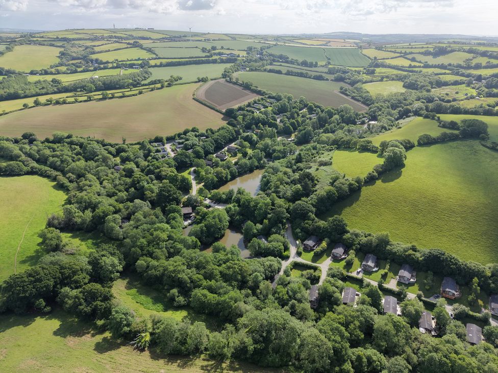 An aerial view of fields, trees, houses, and a pond at 1 Valley View in Lanreath