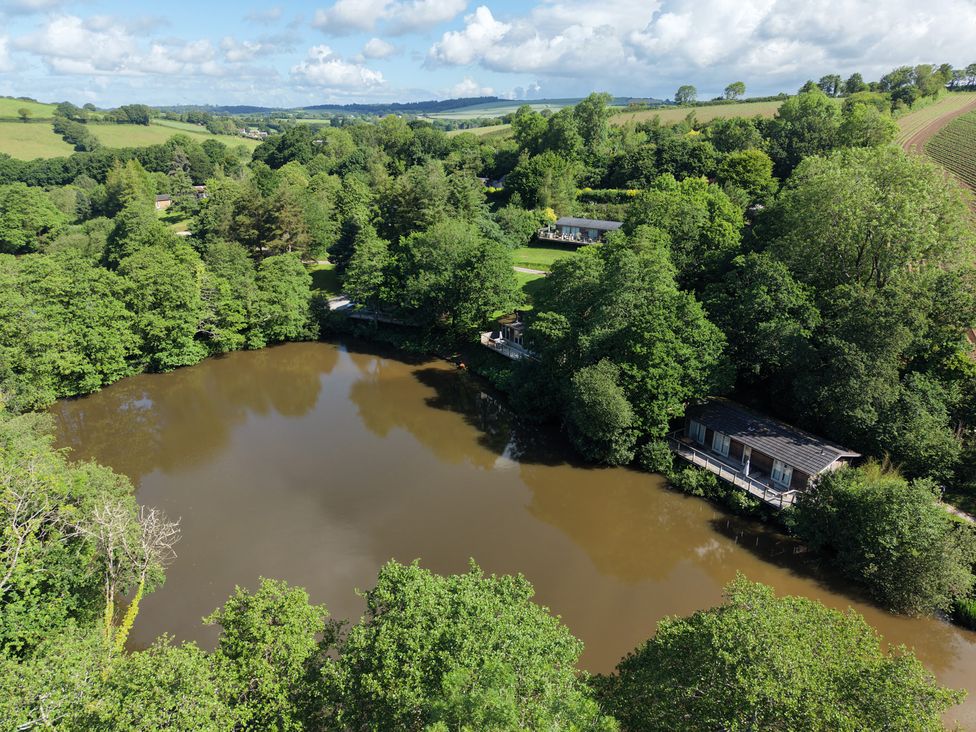 A view of a pond surrounded by trees and houses at 1 Valley View in Lanreath