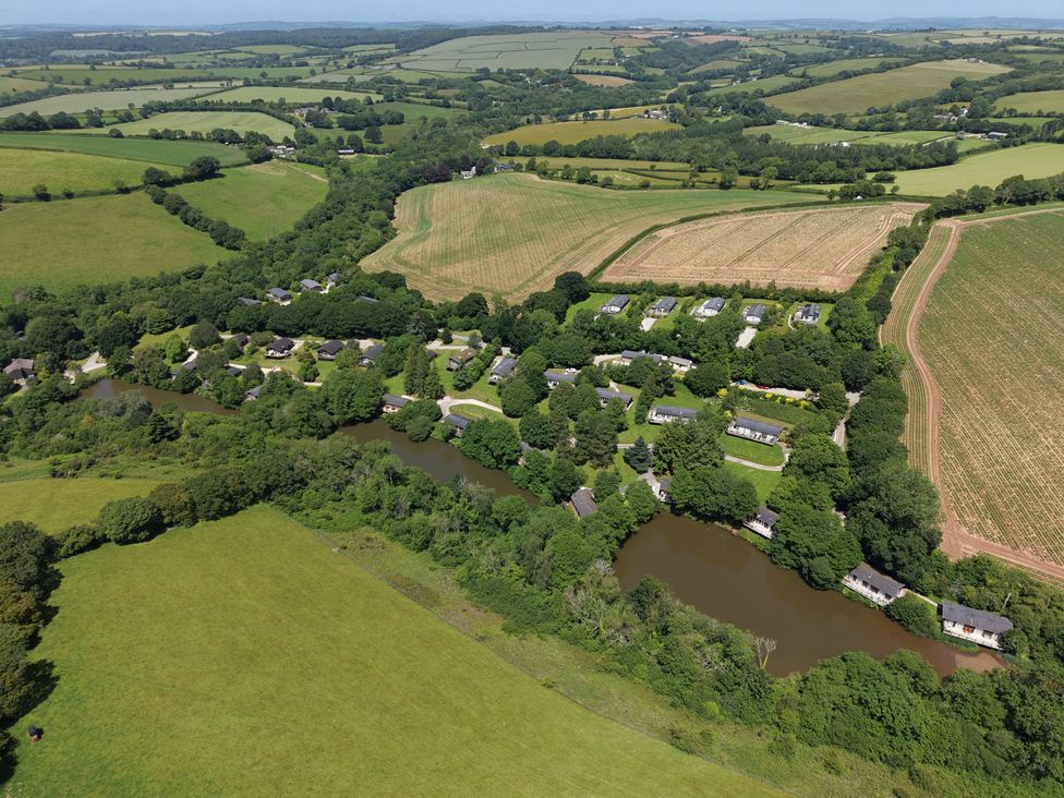 Aerial view of fields, trees, and houses near a river at 1 Valley View in Lanreath