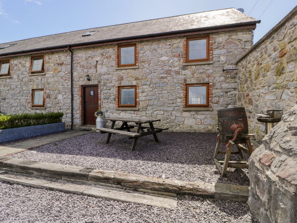 A stone wall house with a garden table and benches at Stabal-y-Gwedd in Dolwen near Abergele