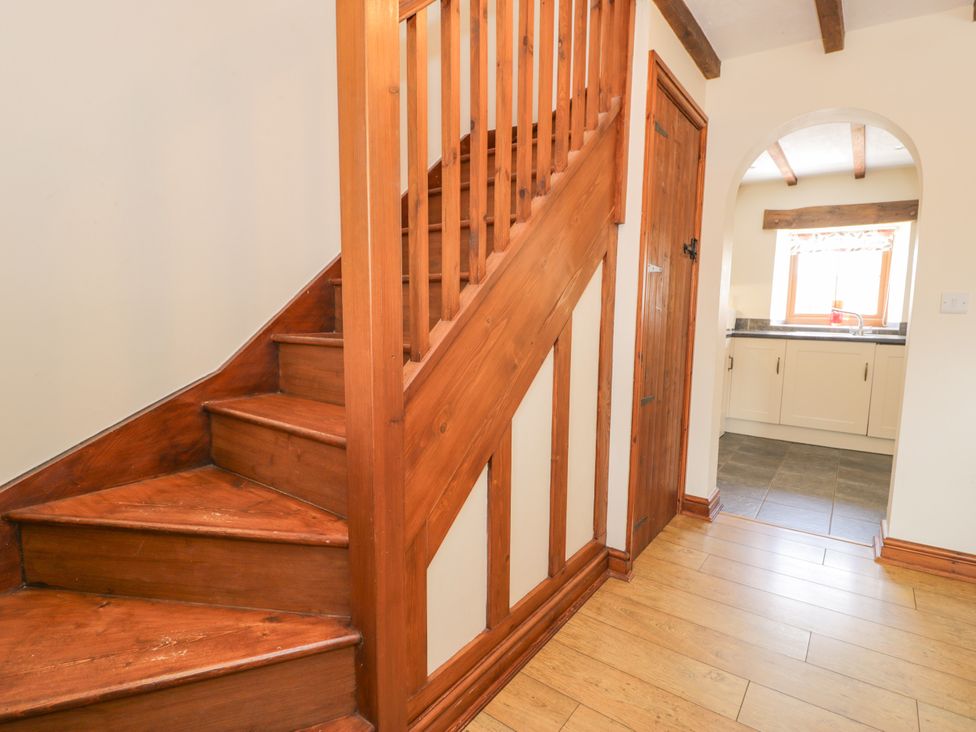 A hallway with stairs and a door leading to the kitchen at Stabal-y-Gwedd in Dolwen near Abergele