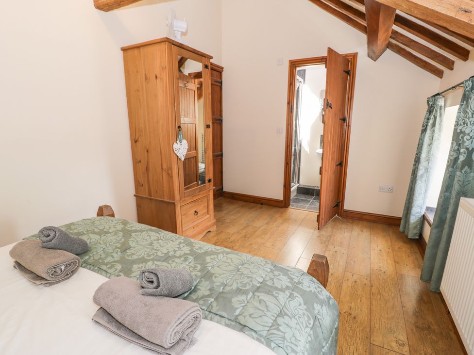 A bedroom with a bed, towels and wardrobe at Stabal-y-Gwedd in Dolwen near Abergele