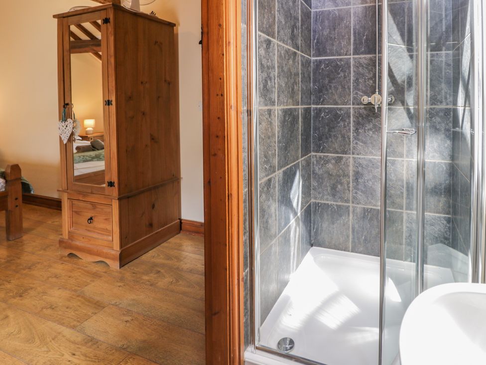 A shower and wooden cabinet in a bedroom at Stabal-y-Gwedd Dolwen near Abergele