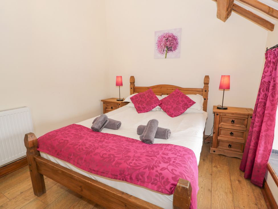 A bedroom with a wooden bed and pink decor at Stabal-y-Gwedd in Dolwen near Abergele