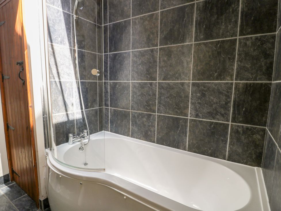 A bathtub with shower in a bathroom at Stabal-y-Gwedd in Dolwen near Abergele