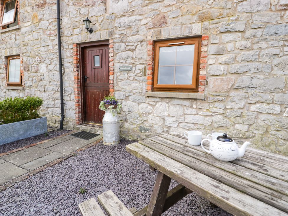 An outdoor area with a table, tea pot, and flower pot at Stabal-y-Gwedd in Dolwen near Abergele